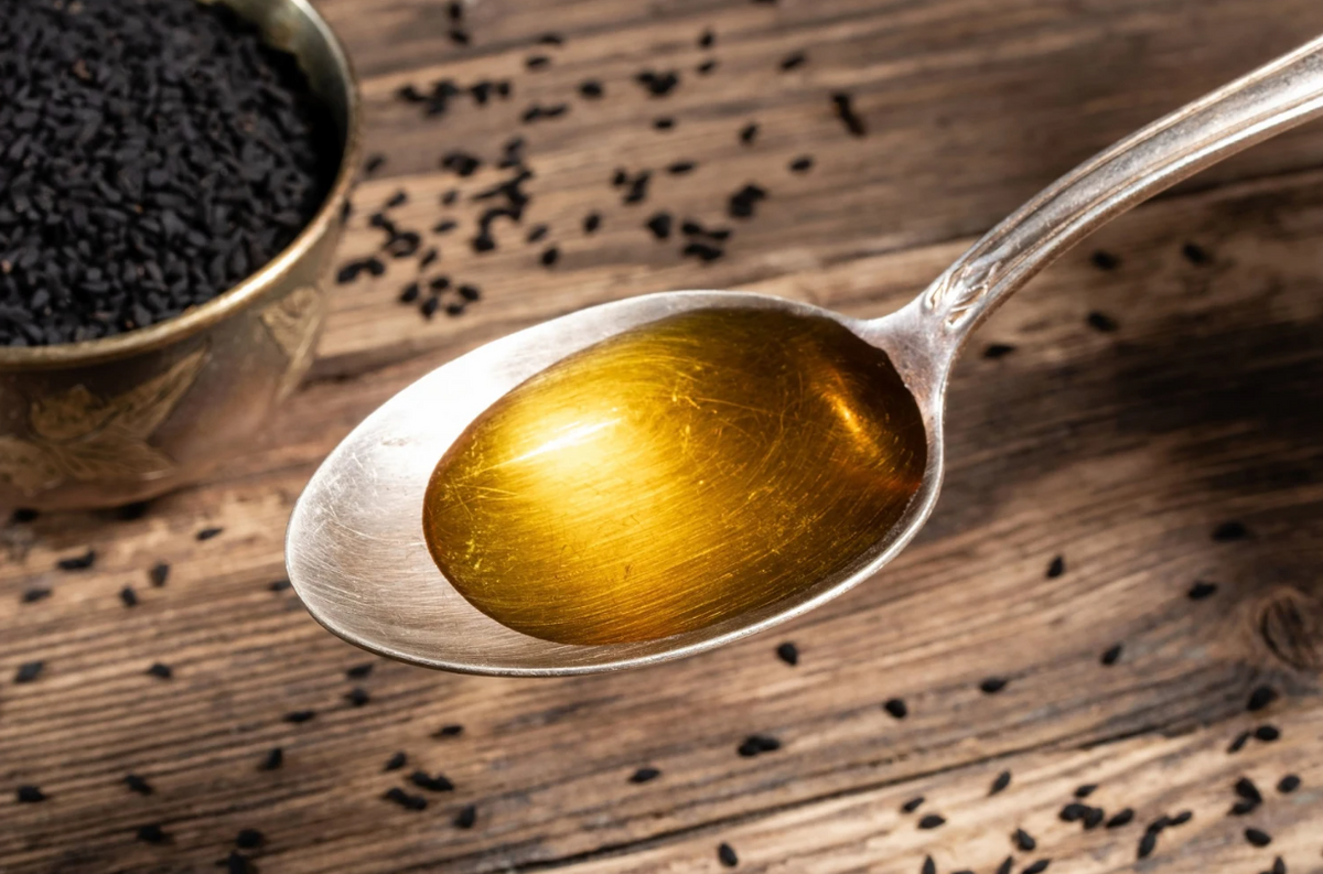 Spoonful of golden black seed oil with Nigella sativa seeds