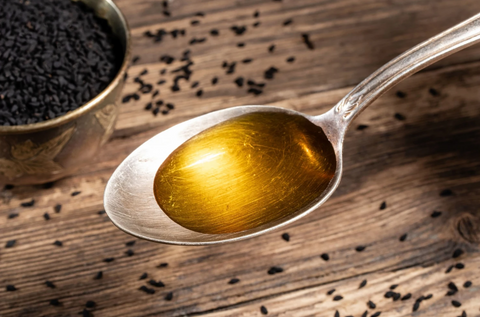Spoonful of golden black seed oil with Nigella sativa seeds